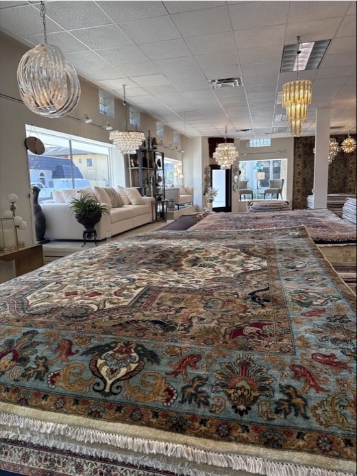 Close showroom view of layered handmade rugs and detailed borders