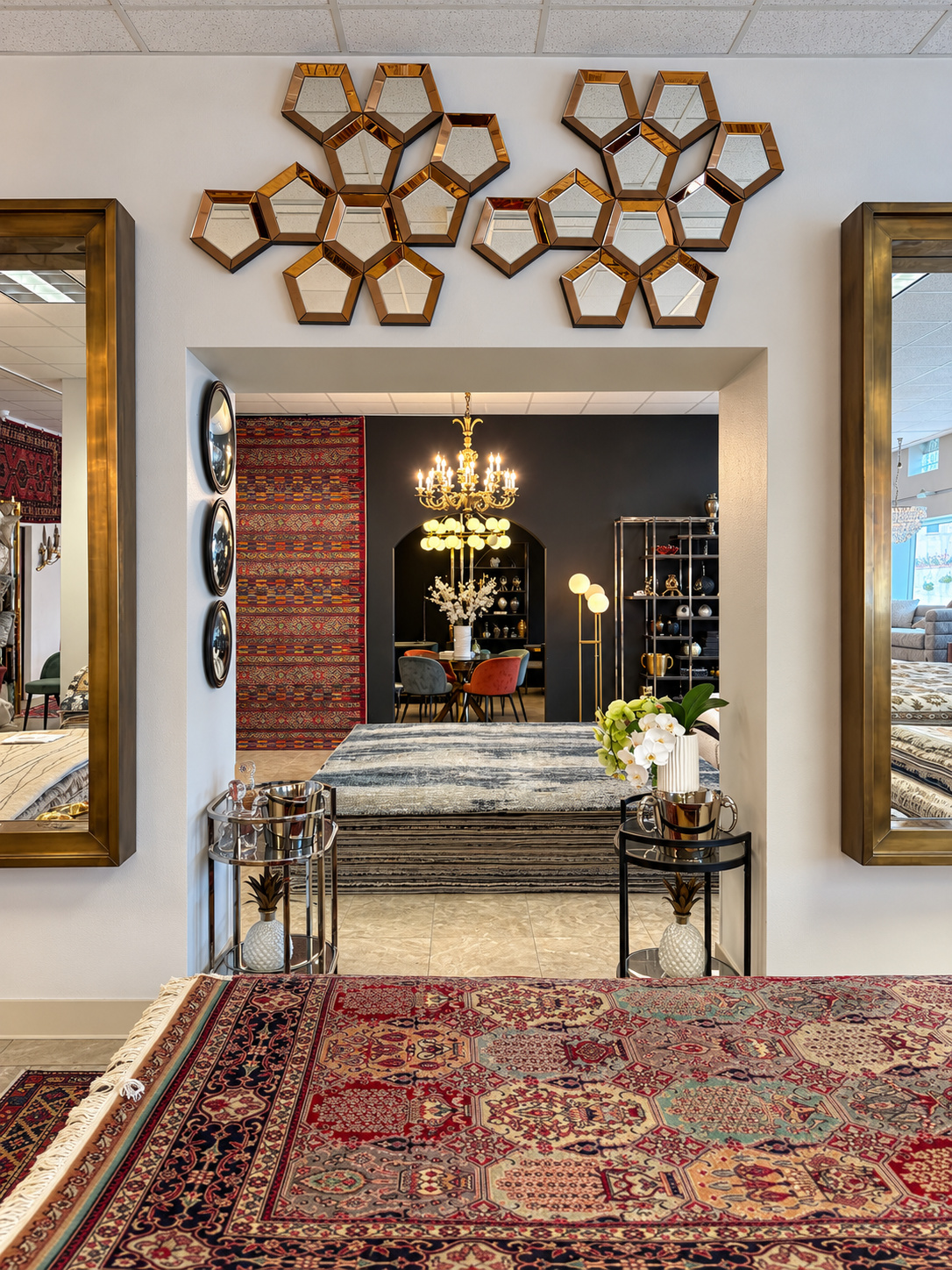 Showroom doorway framed by mirrors with layered handmade rugs and decorative lighting